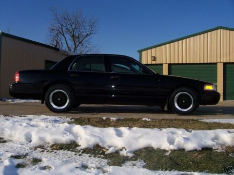 1996 Mercury Grand Marquis - A black 1996 Mercury Grand Marquis sedan is parked outside storage units on a clear day with snow on the ground.