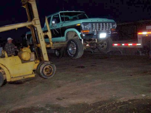 1994 Ford F-150 - A forklift lifts a vintage Ford pickup truck, likely from the late 1970s.