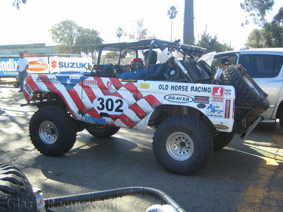 Side view of stars-and-stripes Bronco race truck number 302 with roll cage