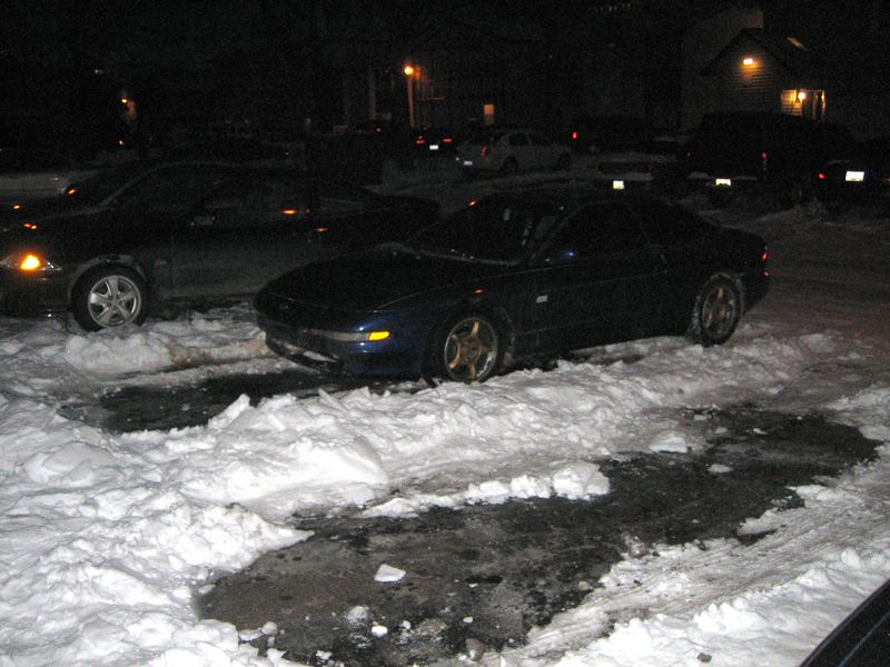 Dark blue coupe parked in snow next to a black car