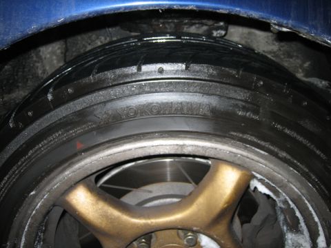 1995 Ford Probe - A close-up view of a Yokohama tire mounted on a gold multi-spoke wheel, with a blue fender visible above.