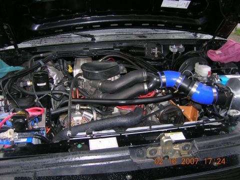 1996 Ford Bronco - The engine bay of a vehicle, prominent blue intake hoses and various engine parts.