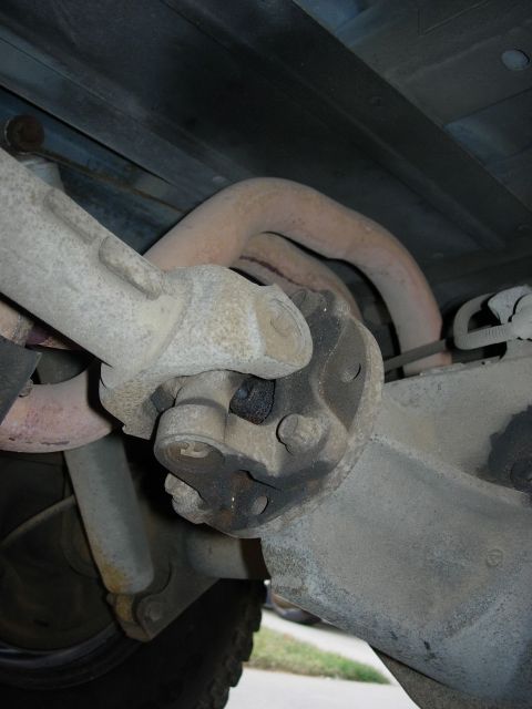 1990 Ford Bronco - Underside view of a vehicle's driveshaft U-joint and exhaust system components.