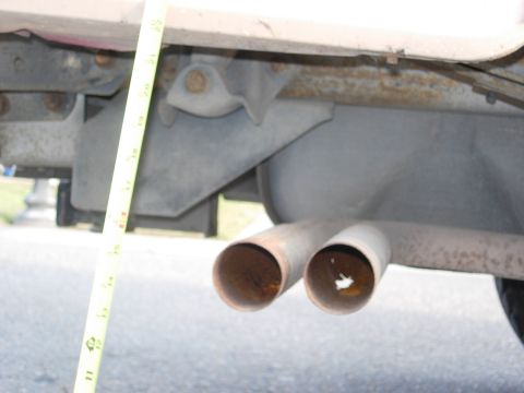 1990 Ford Bronco - Undercarriage view of dual exhaust pipes with a measuring tape indicating a dimension.