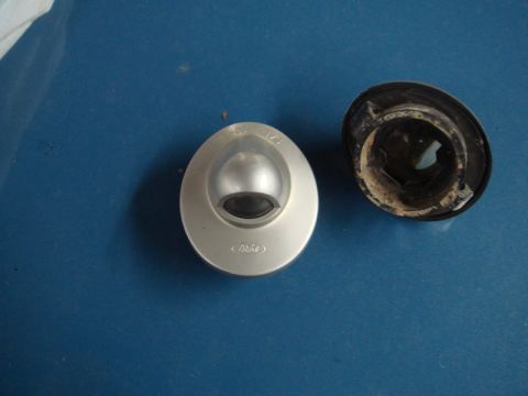 1996 Ford Bronco - A Ford license plate light assembly and its housing sit on a blue surface. Part numbers are visible on the assembly.