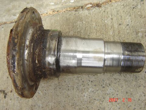 1993 Ford Bronco - A close-up of a used metal axle part, showing wear and rust, resting on a concrete surface.