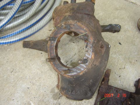 1993 Ford Bronco - Close-up of a heavily rusted automotive part with visible bolt holes and a central opening.