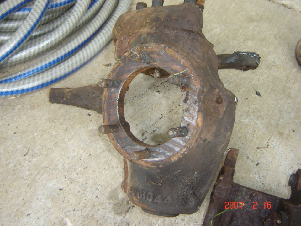 rusted metal part with bolts and a circular opening, part number visible