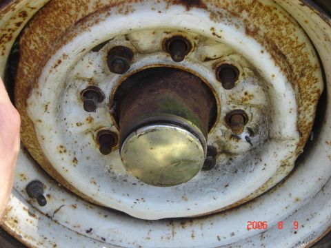 1993 Ford Bronco - A close-up view of a rusty wheel hub with a shiny center cap and six lug nuts is visible in this image.