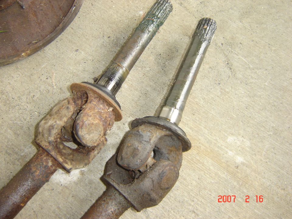 Two CV axles, one rusty and one cleaned, on a concrete surface