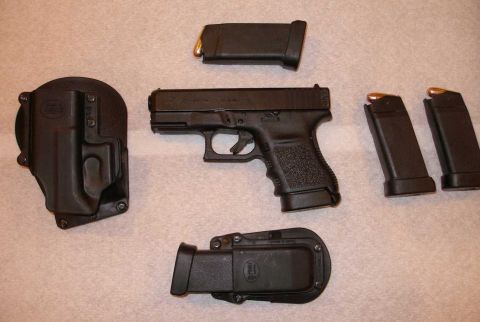 1998 Ford Crown Victoria - A handgun with accessories is displayed on a surface, with a watermark indicating 'SuperMotors.net'.
