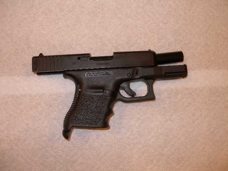 Black semi-automatic pistol on a beige surface, side view