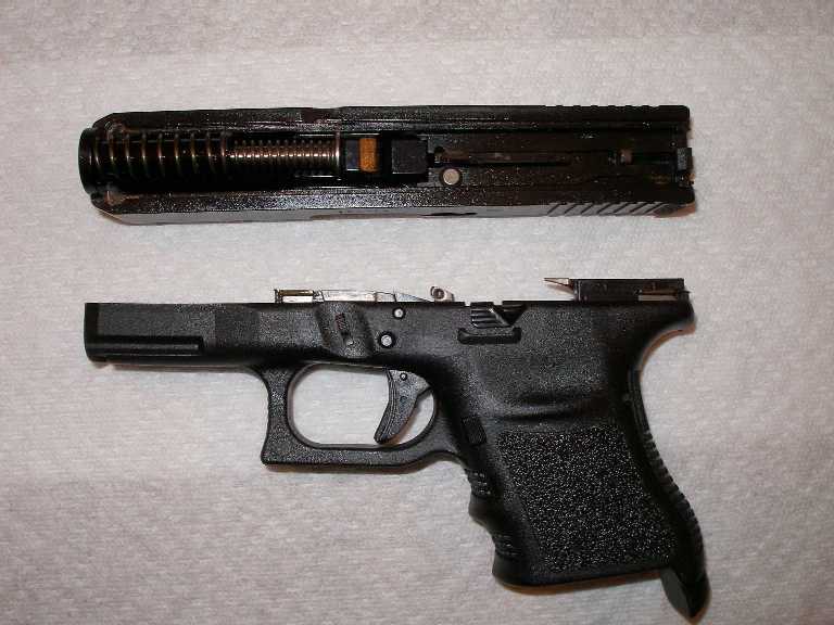 Disassembled black semi-automatic pistol with slide and frame on a white towel