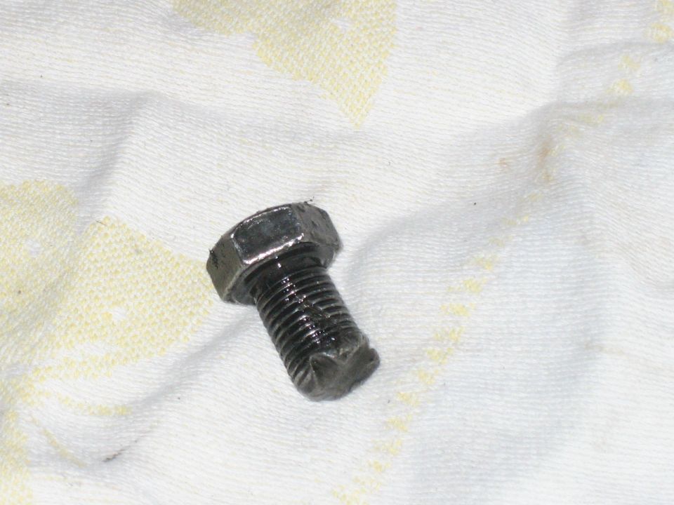 Greasy bolt on a white cloth with yellow stains. Supermotors.net logo in lower right