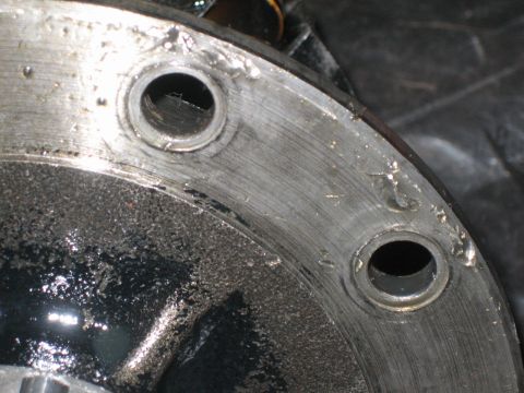 1995 Ford Bronco - Extreme close-up of a freshly machined bare-metal flange face with two counterbored bolt holes, showing concentric lathe or mill tool marks…