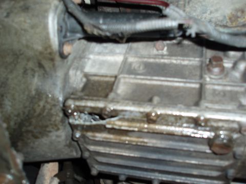 1985 Ford Bronco II - Close-up view of a damaged transmission casing showing an oil leak.