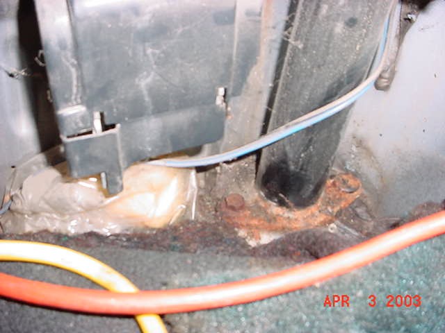 Roll bar tube and rusty mounting base on a corroded floor pan, date-stamped April 2003