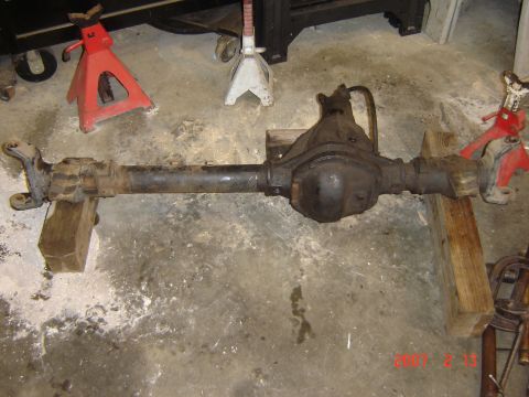1993 Ford Bronco - A rear axle assembly is shown supported by wooden blocks and jack stands in a garage setting.