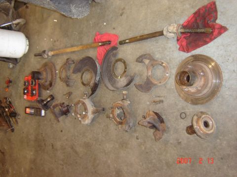 1993 Ford Bronco - Various disassembled vehicle suspension and brake parts are arranged on a garage floor.