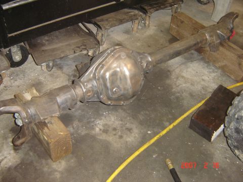 1993 Ford Bronco - A bare metal differential axle assembly is shown resting on wooden blocks in a garage setting.