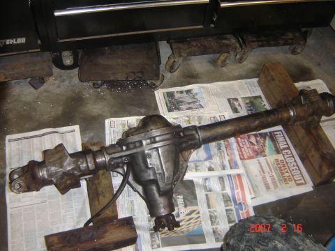 1993 Ford Bronco - A rear axle assembly is shown disassembled and resting on newspapers, with wooden blocks providing support.