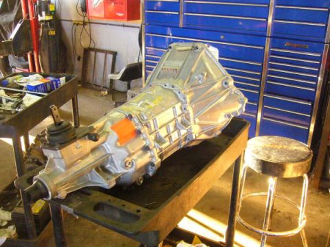 1996 Mercury Grand Marquis - A transmission with a manual shifter is displayed on a workbench in a garage setting.