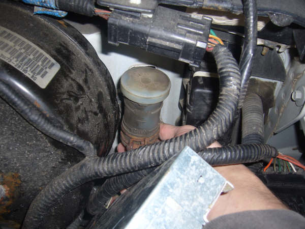 Under-hood shot of master cylinder reservoir surrounded by wiring harness and connectors
