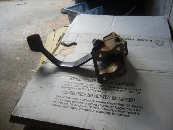 Black pedal with steel mounting bracket on cardboard box
