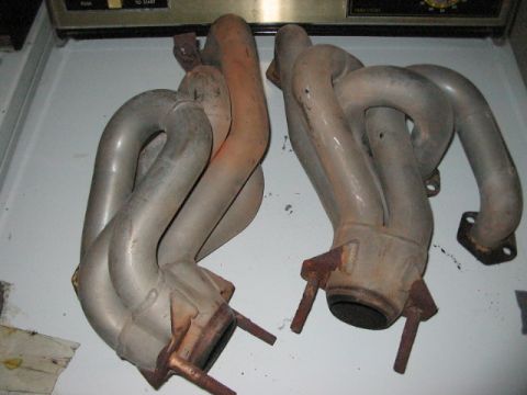 1991 Ford Bronco - A pair of exhaust manifolds are shown, one exhibiting rust-colored discoloration from heat.
