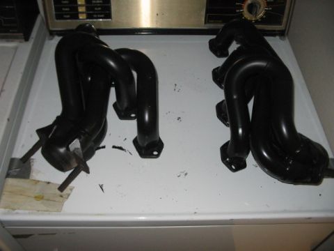 1991 Ford Bronco - A pair of black exhaust headers are displayed on a white surface, possibly a laundry room counter.