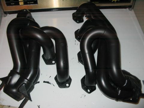 1991 Ford Bronco - Two black exhaust headers are displayed on a white surface, with a control panel visible above.