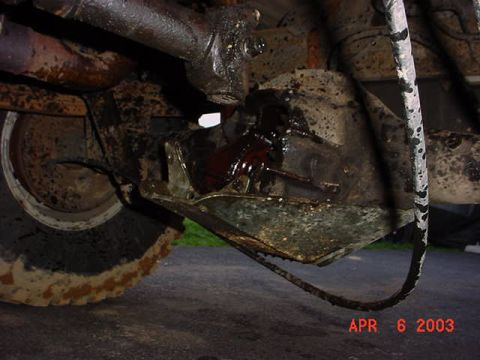 1980 Ford Bronco - Underbody shot of a rear axle housing with the differential cover removed, exposing the ring gear and carrier with gear oil running down th…