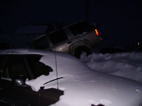 2000 Chevrolet Tahoe - A silver SUV is stuck in a snowdrift at night, with another vehicle partially visible in the foreground.