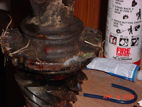 1980 Ford Bronco - Close-up of a dirty, grease-caked axle differential ring-and-pinion assembly sitting on a wooden workbench, with the pinion gear teeth and…