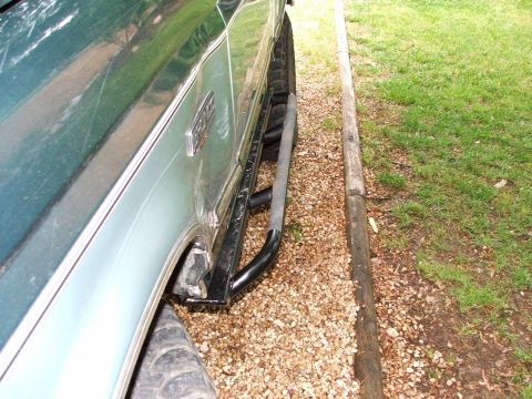 1996 Ford Bronco - The side of a 1996 Ford Bronco is visible, a slider bar and gravel on the ground.