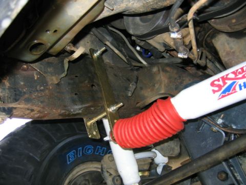 1989 Ford Bronco - Undercarriage detail of a vehicle, focusing on a shock absorber and tire.