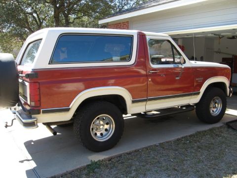1986 Ford Bronco - This two-tone Ford Bronco is parked outside a garage.