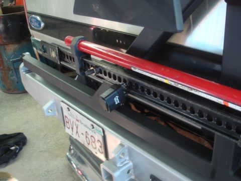 1996 Ford Bronco - Close-up of a steel rear bumper with a red hi-lift jack mounted above a New Brunswick plate reading BVX-683.