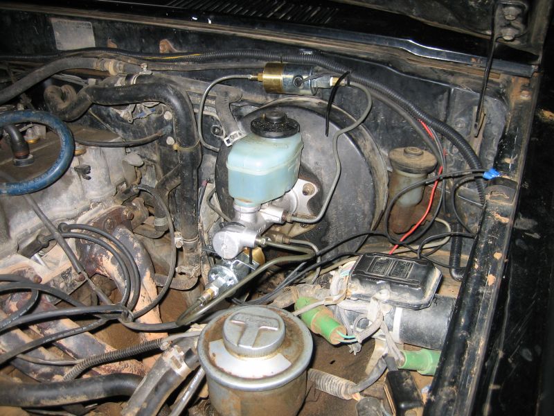 Engine bay view of brake master cylinder and hoses. Text 'SUPERMOTORS' visible