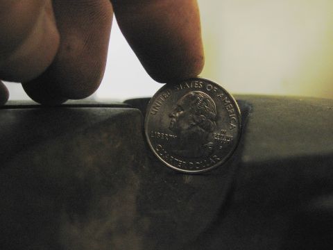 1974 Ford F-100 - A quarter dollar coin is placed on a dark surface, showing visible text and George Washington's profile.