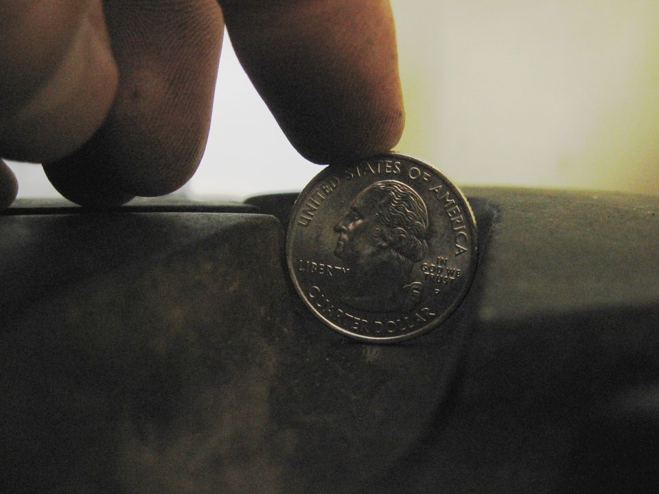 Quarter dollar coin on a dark, textured surface. Text 'UNITED STATES OF AMERICA' and 'QUARTER DOLLAR' is visible
