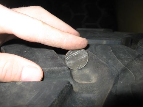 1974 Ford F-100 - A coin is used to measure the tread depth of a vehicle's tire.