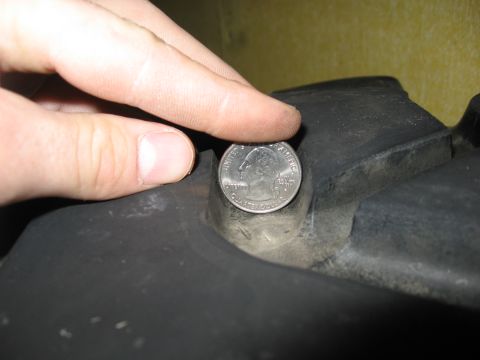 1974 Ford F-100 - A quarter is used to show the size of a recess in a black plastic automotive part.