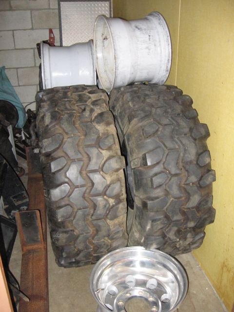 1974 Ford F-100 - Off-road tires and rims are stored indoors against a yellow wall and brick wall.