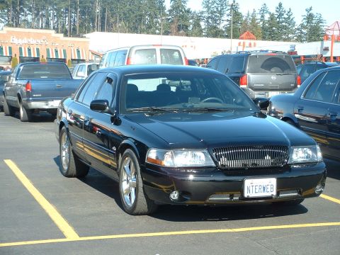 2000 Ford Crown Victoria - A black 2000 Ford Crown Victoria is parked in a lot, showing its distinctive grille and front end.