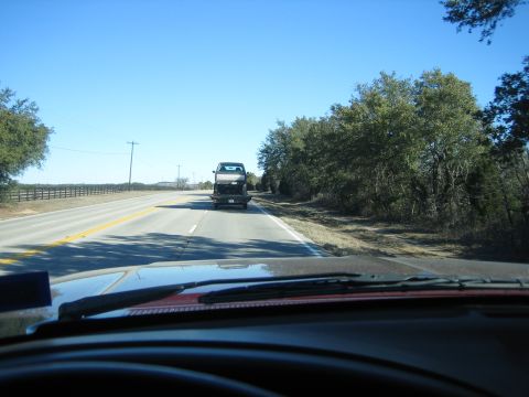 1996 Ford Bronco - Truck being transported on a flatbed trailer down a highway on a clear day.