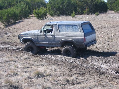 1996 Ford Bronco - A gray Ford Bronco is stuck in thick mud off-road.