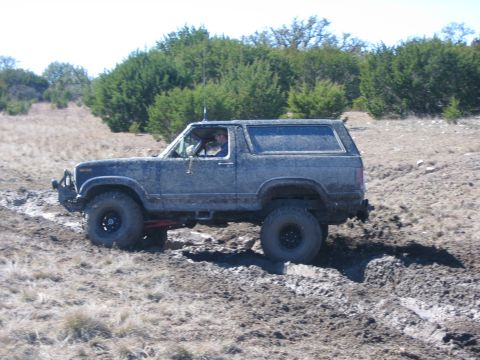 1996 Ford Bronco - This SUV is navigating a muddy off-road trail, its capabilities.