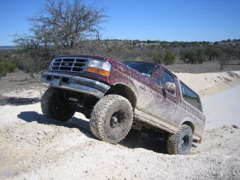 1996 Ford Bronco - This 1996 Ford Bronco is navigating a challenging off-road terrain with a clear blue sky above.