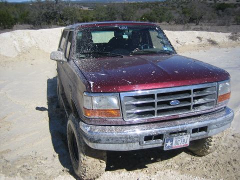 1996 Ford Bronco - A 1996 Ford Bronco is shown in a 3/4 front view, covered in white splatter and parked in a dirt area.